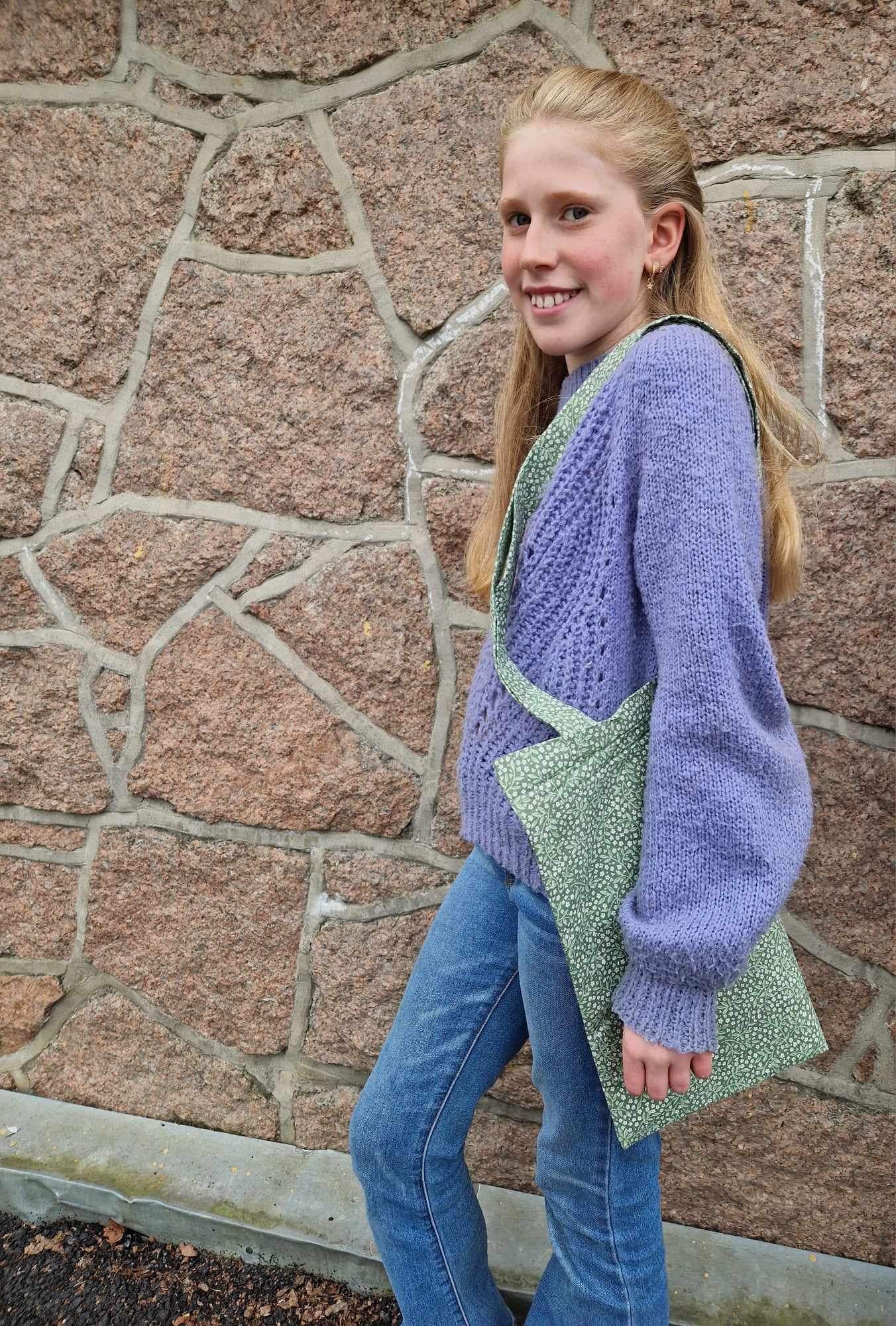 en person som smiler og står foran en murvegg