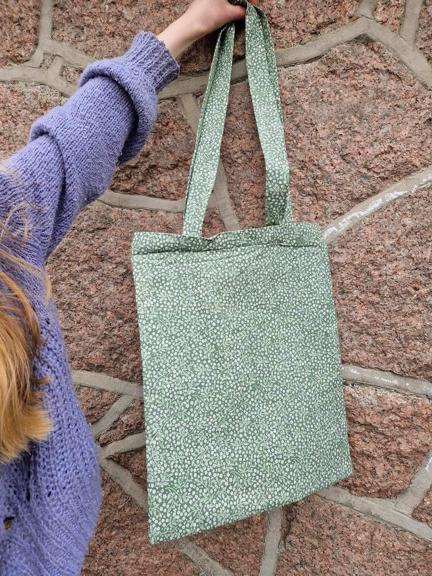 en hånd som holder en grønn pose