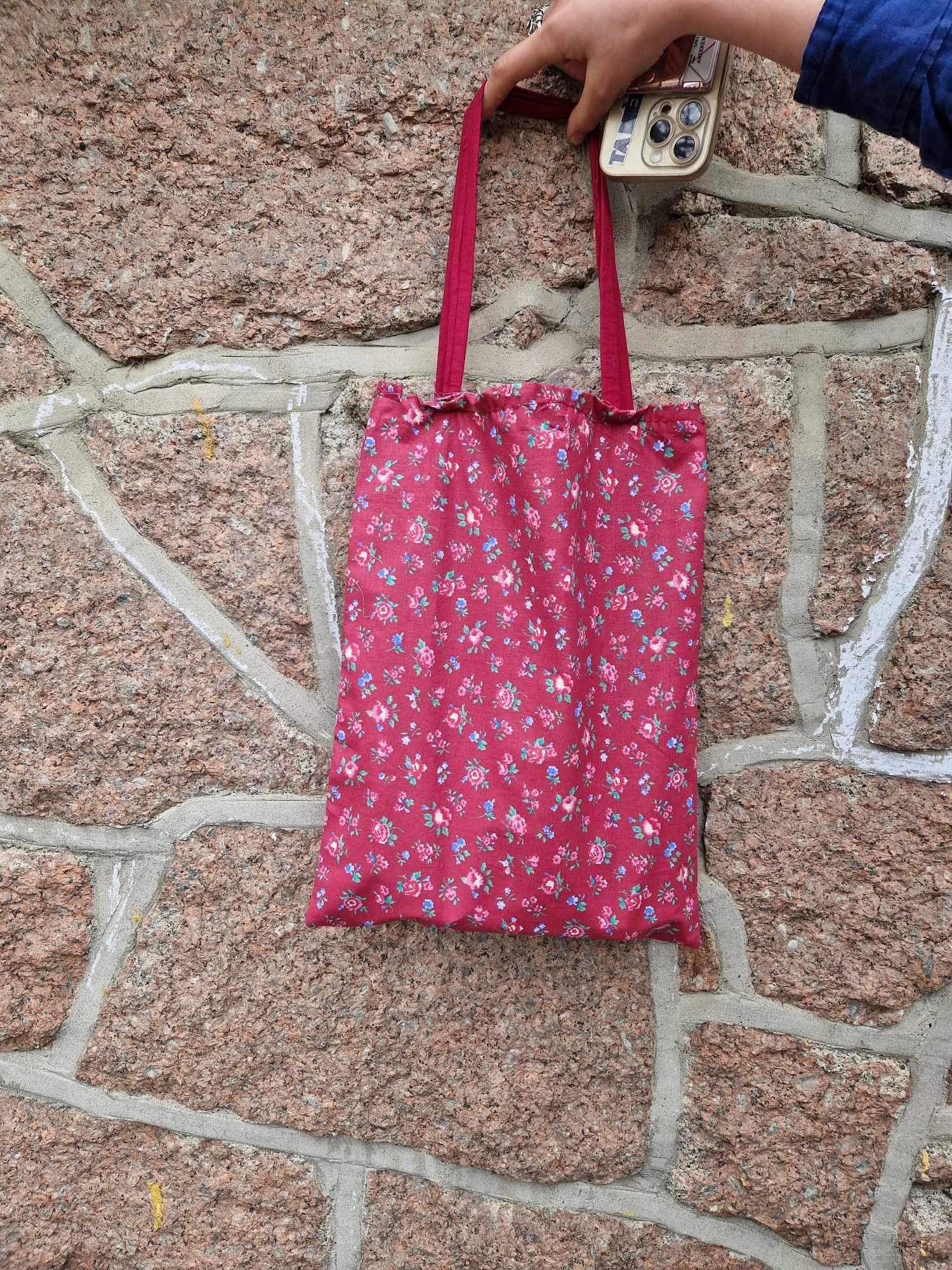 en hånd som holder en rød og hvit handlepose