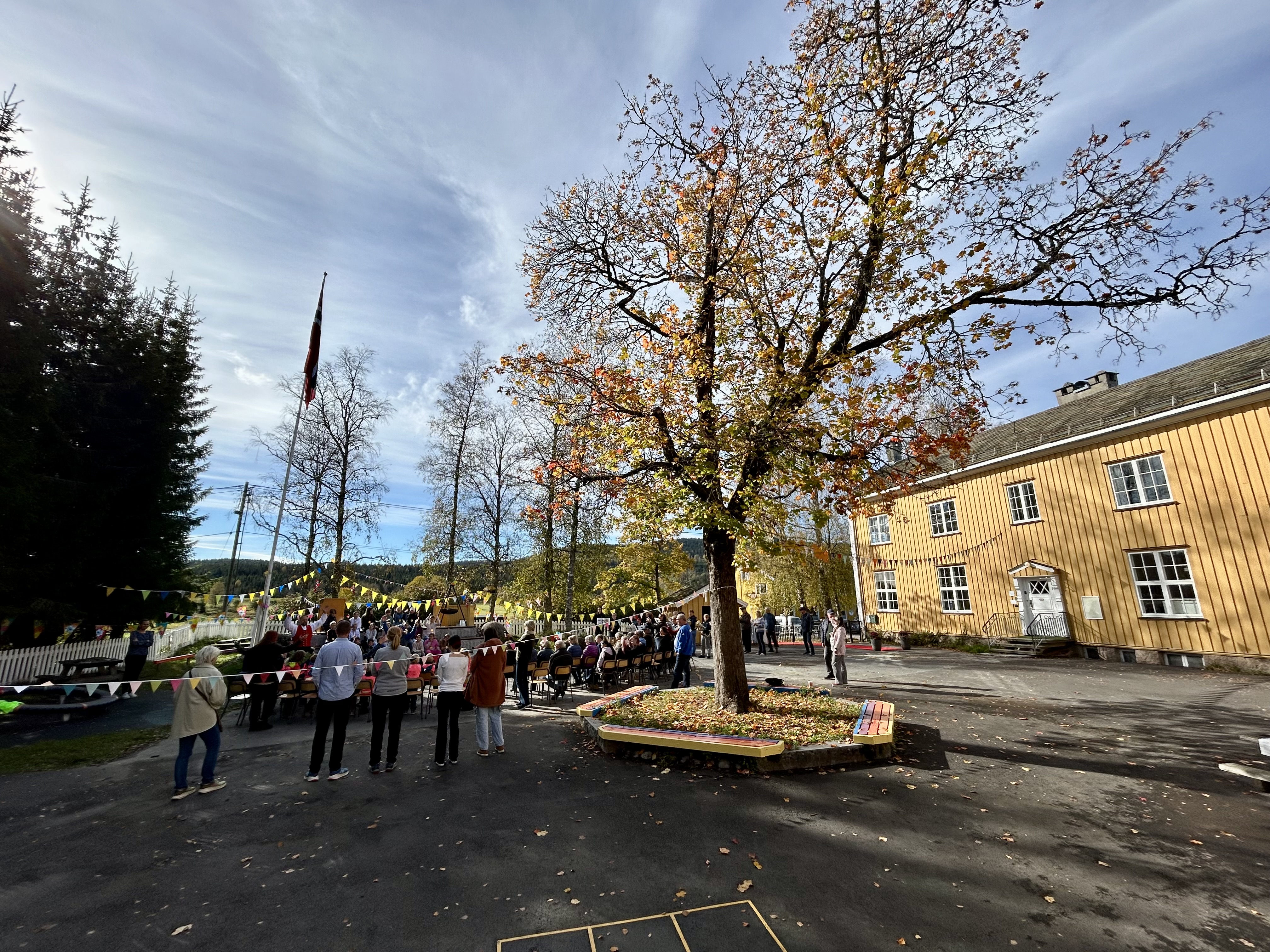 en gruppe mennesker som står rundt et tre på en gårdsplass