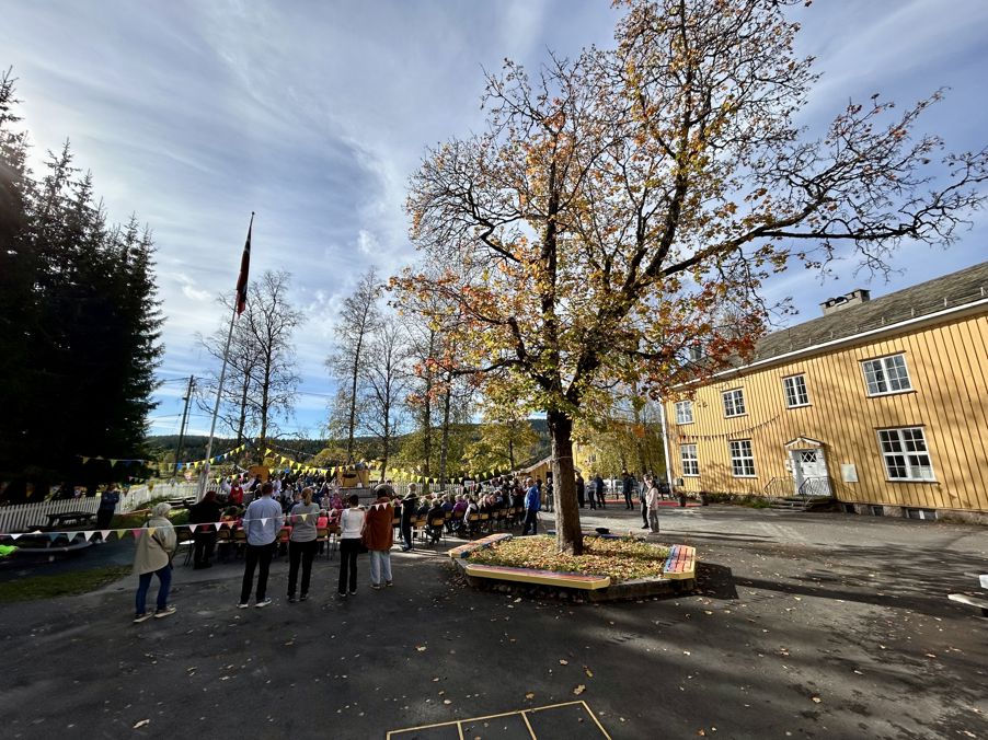 en gruppe mennesker som står rundt et tre på en gårdsplass en gruppe mennesker som står rundt et tre på en gårdsplass