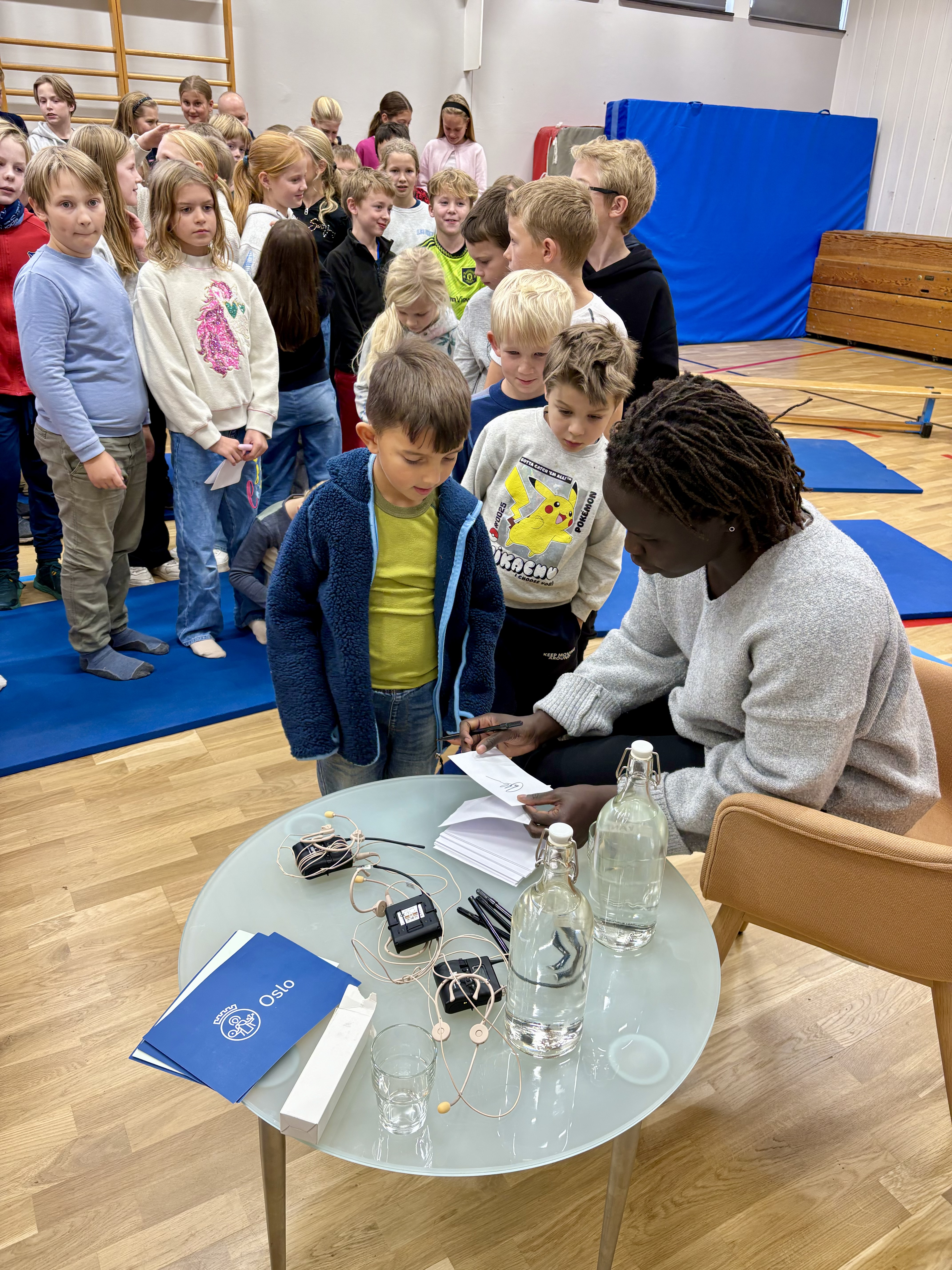 en gruppe mennesker som står rundt et bord med en person som sitter ved det