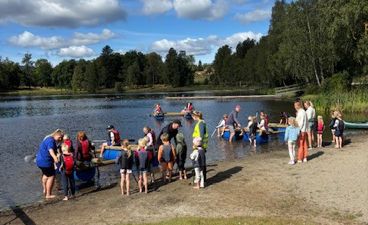 en gruppe mennesker som står på en brygge ved en innsjø