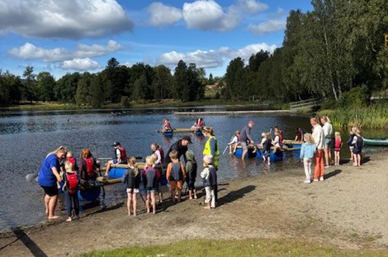 en gruppe mennesker som står på en brygge ved en innsjø