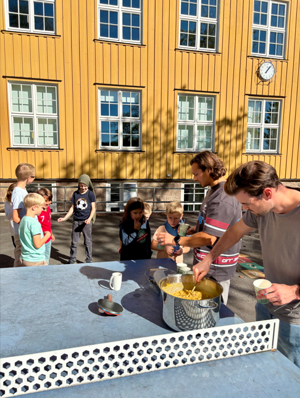 en gruppe mennesker som står rundt et bord med mat på