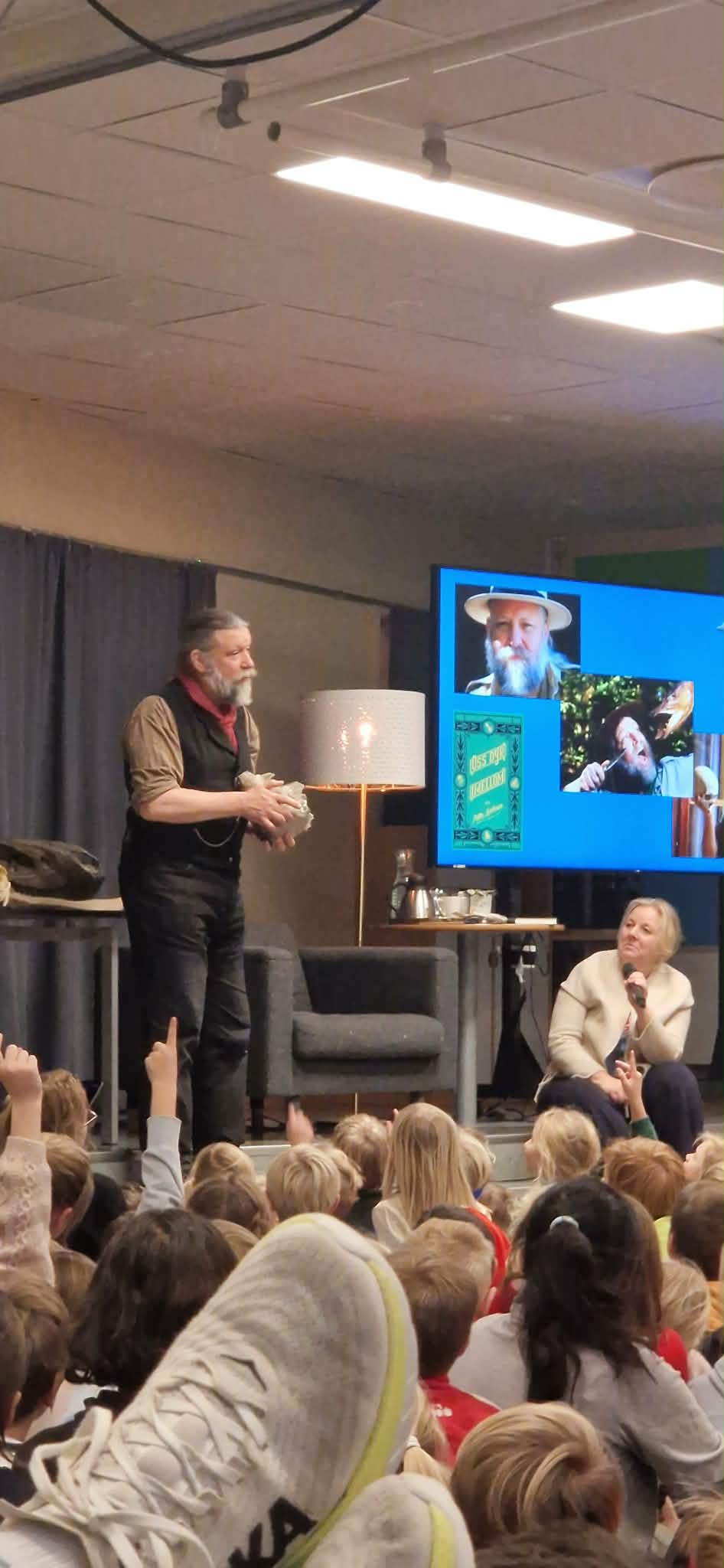 En person som snakker til en gruppe mennesker i et rom med en stor skjerm