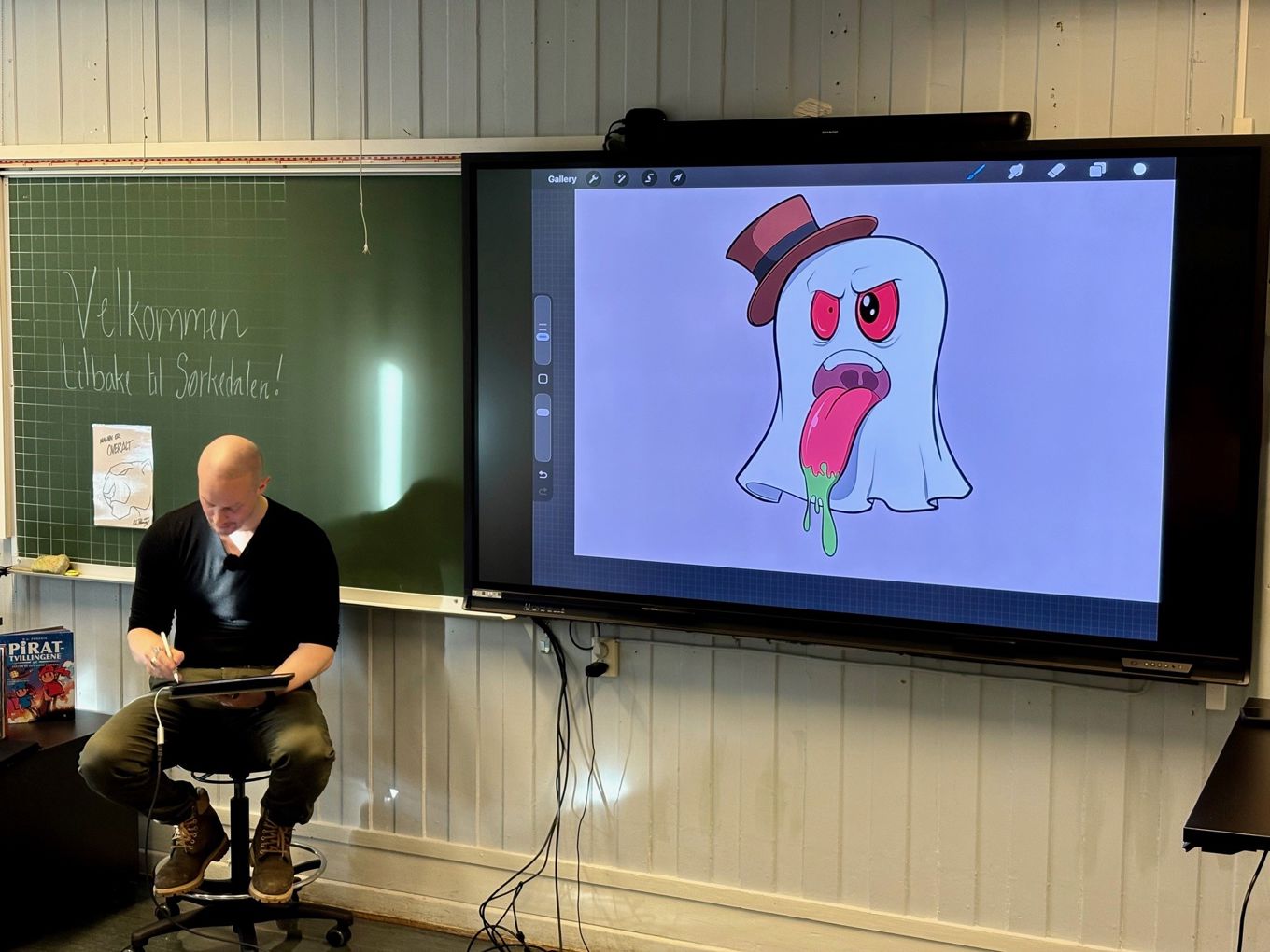 en person som sitter på et skateboard foran en projeksjonsskjerm