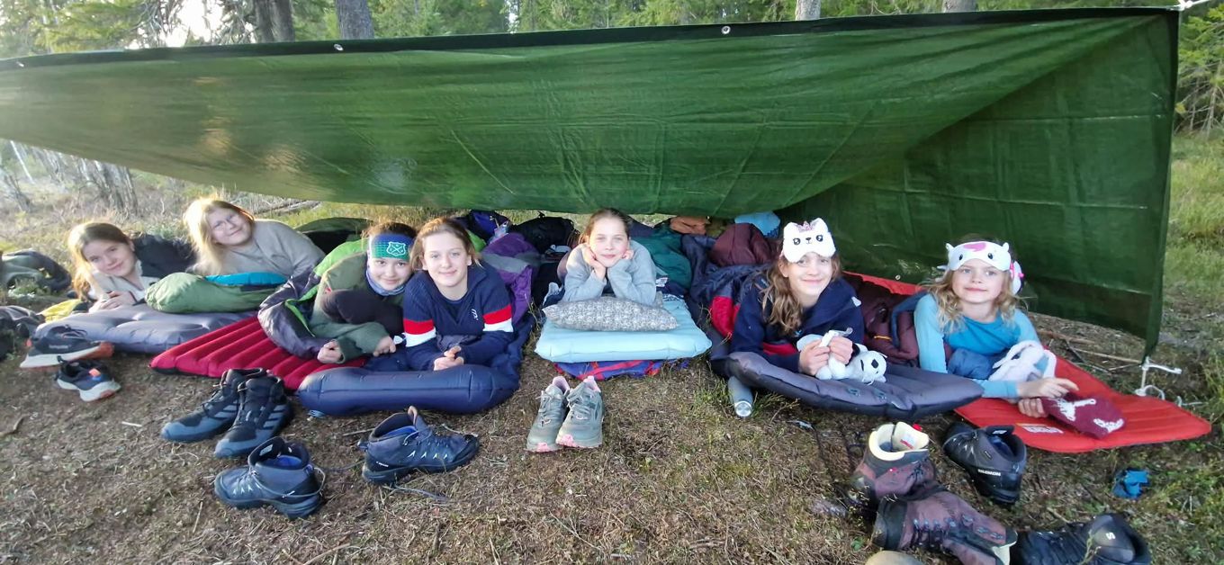 En gruppe barnr som sitter på et teppe i gresset